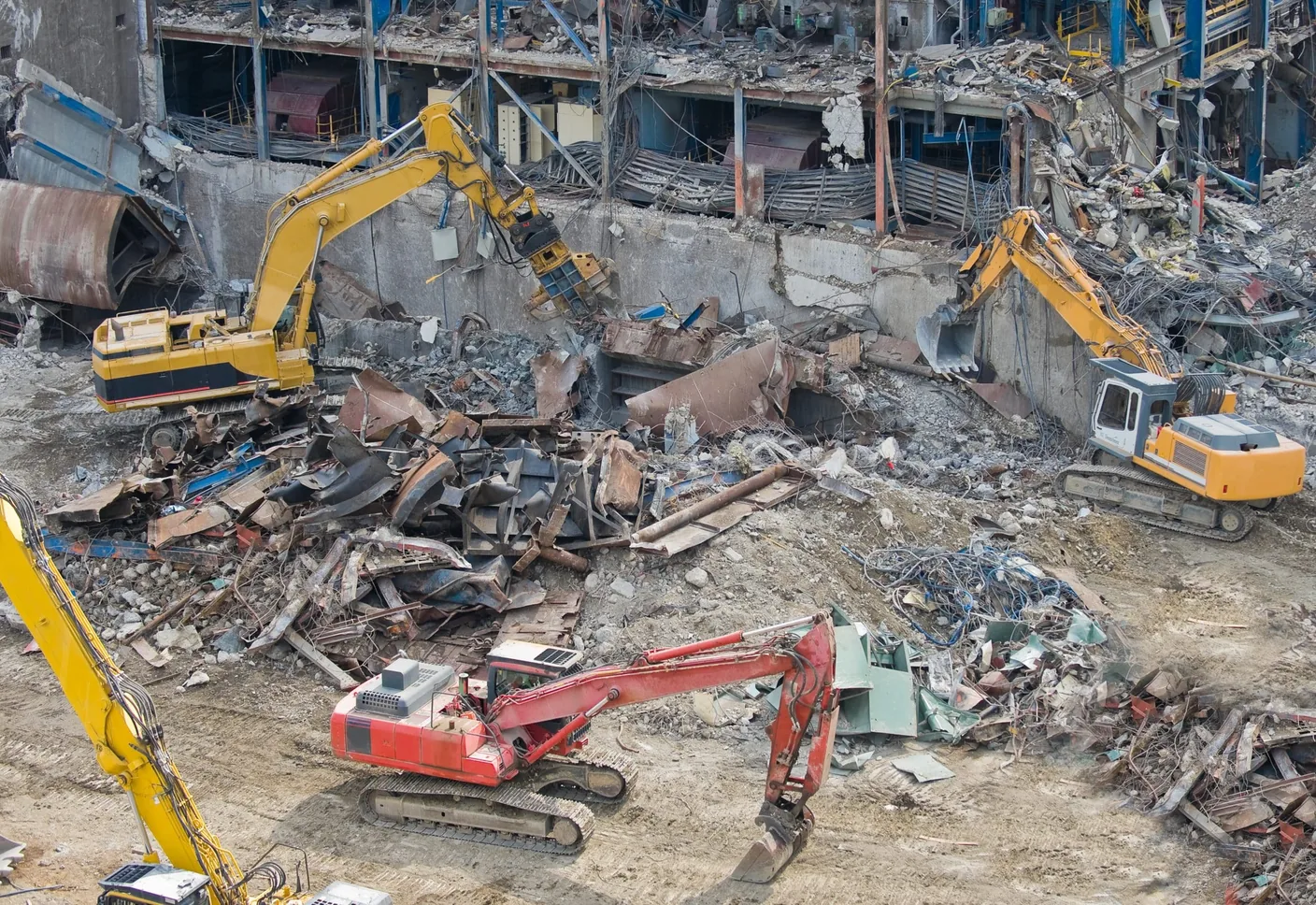 Aerial view of a large demolition site with excavators and debris piles