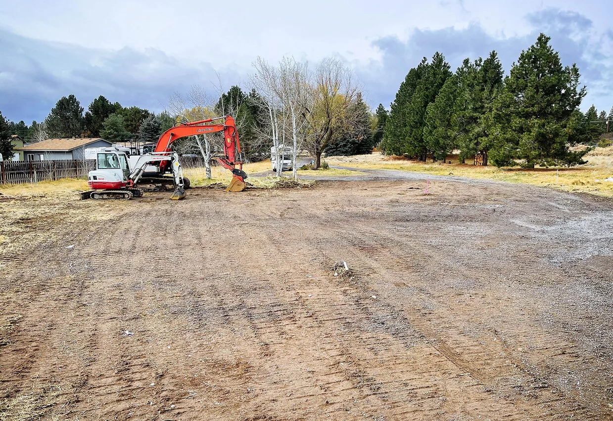 Excavator parked on the bare graded ground left after a slab was removed