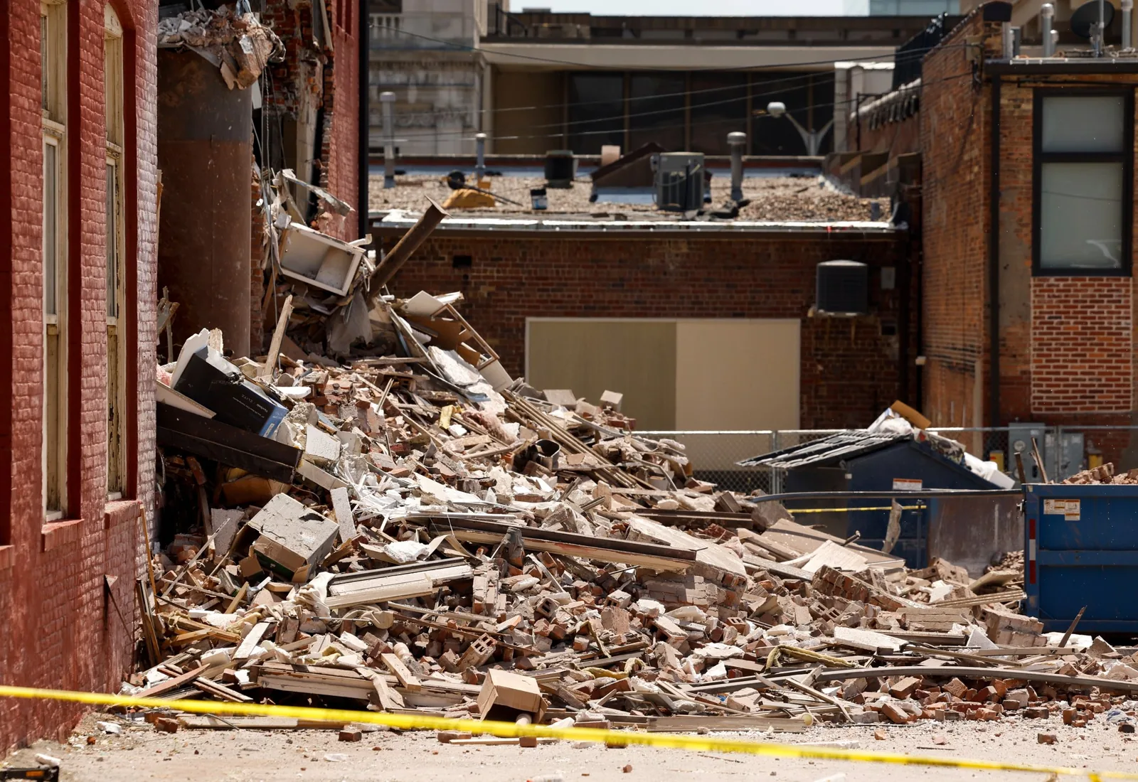 Partly demolished brick building with a large debris pile in front of it