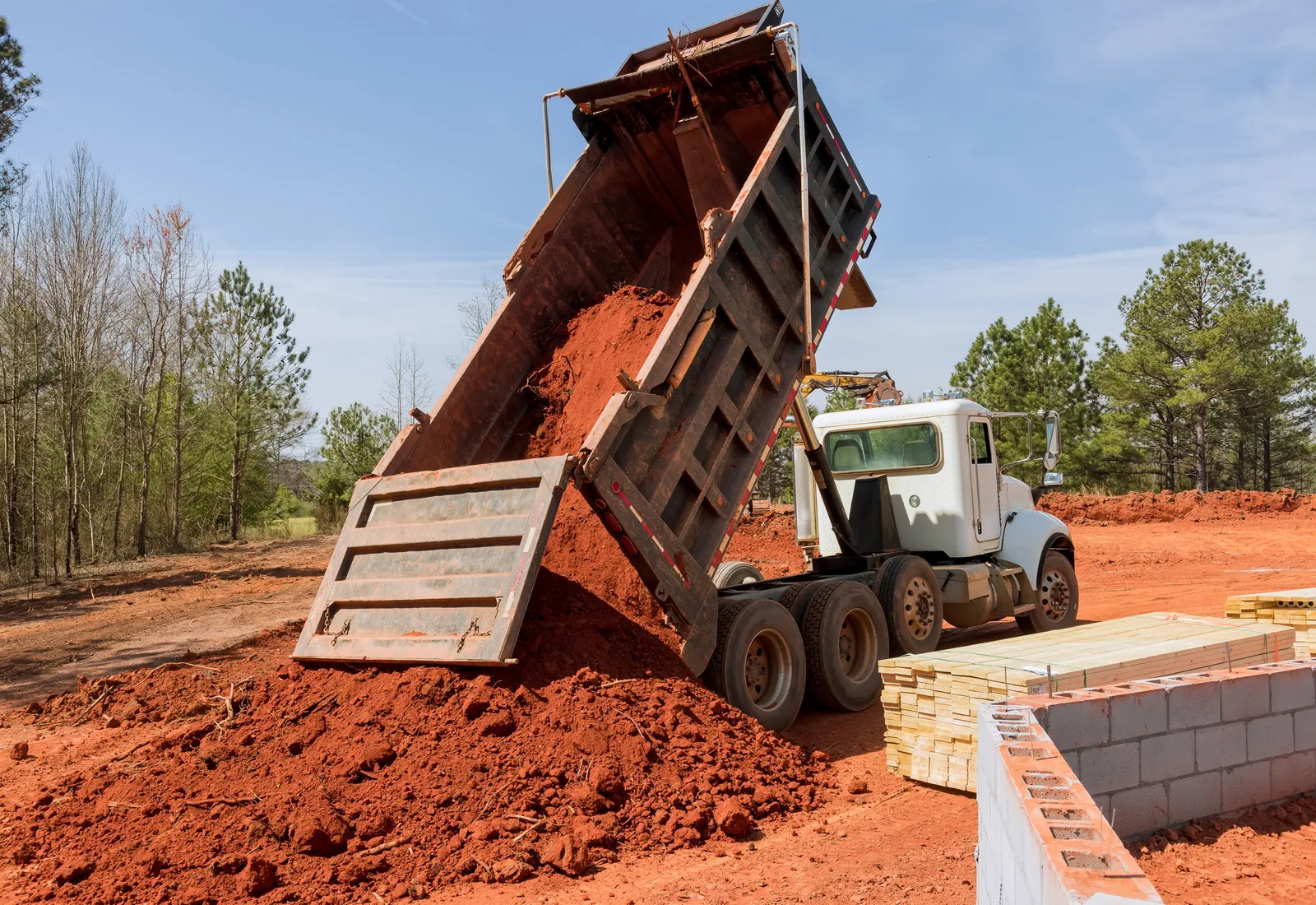 Tandem dump truck dumping a load of fill dirt on a building site