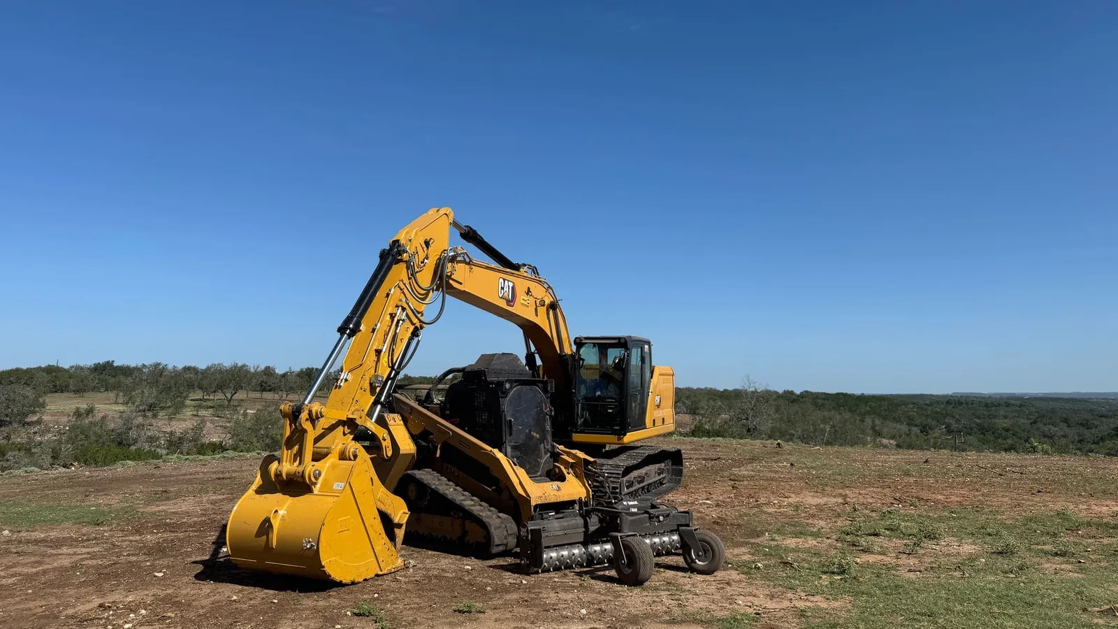 Excavator fitted with a mulching head on a cleared hilltop