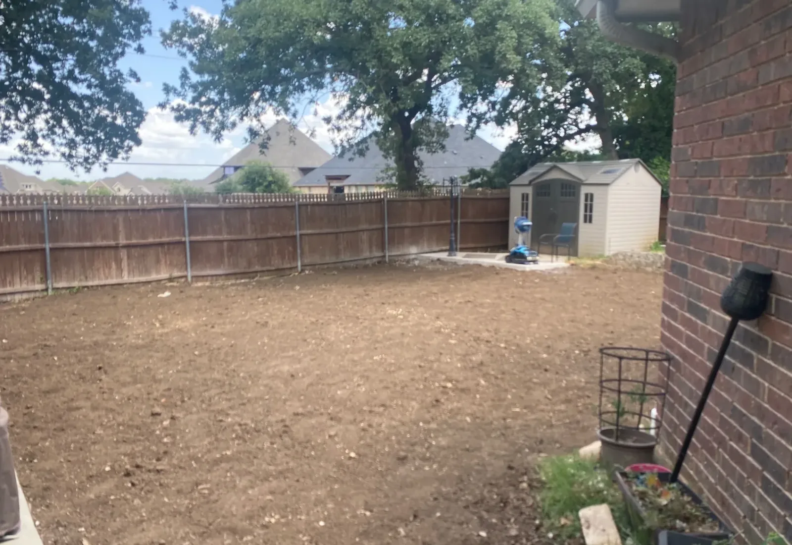 Bare graded backyard behind a brick house after a pool was removed