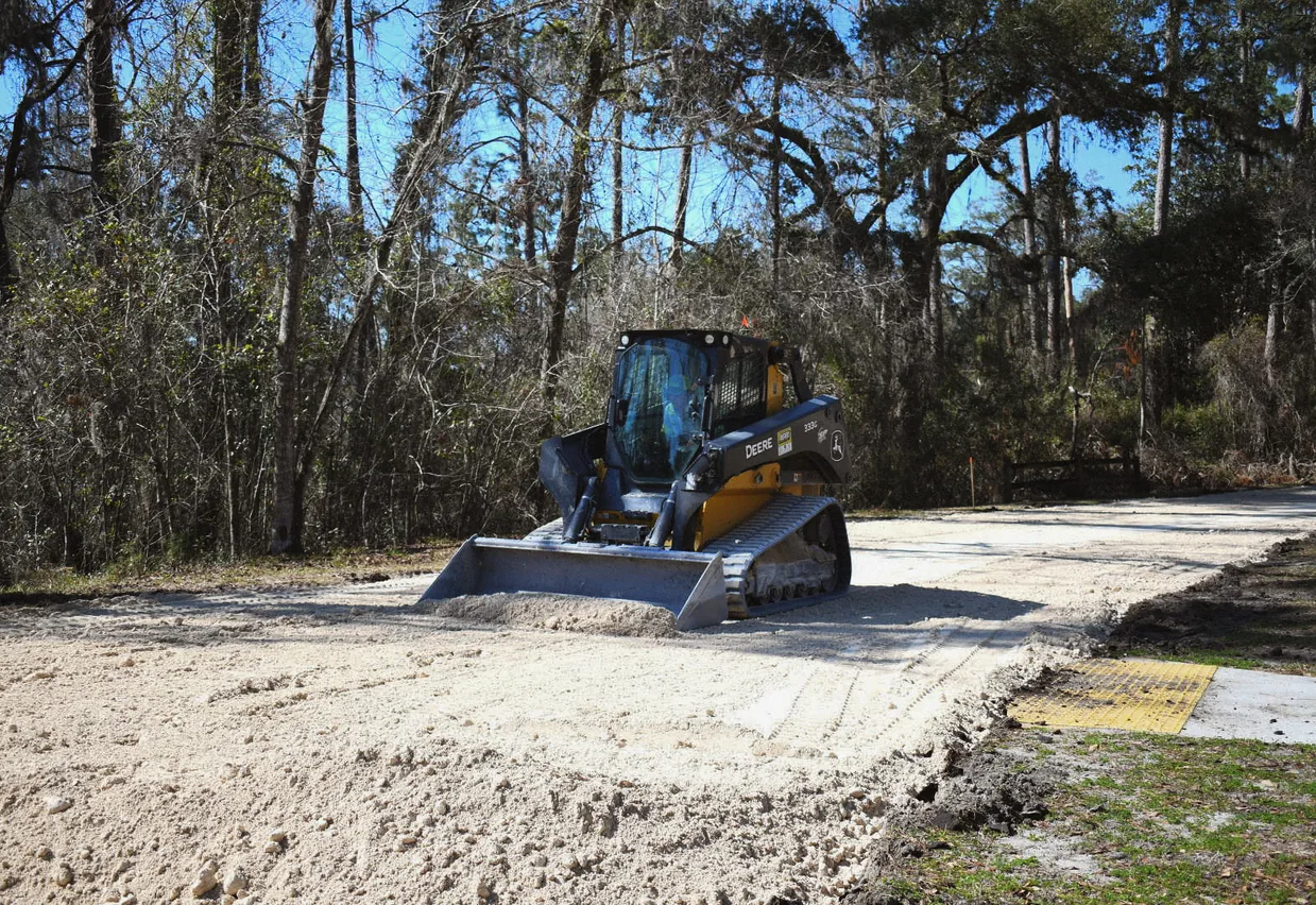 Compact track loader finish-grading a sandy building lot